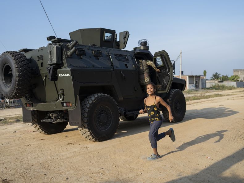 Una niña pasa corriendo junto a una patrulla militar en la ciudad de Durán, ubicada frente a Guayaquil, Ecuador, el 30 de septiembre de 2023. (AP Foto/Rodrigo Abd)