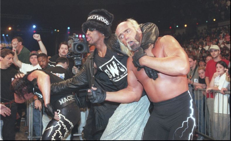 ARCHIVO - La estrella del baloncesto Dennis Rodman (centro) ayuda a su equipo de lucha libre a regresar al ring el 16 de marzo de 1997, durante el PPV de World Championship Wrestling en el North Charleston Coliseum de Charleston, Carolina del Sur. A la izquierda, Randy Macho Man Savage, y a la derecha, su compañero Hulk Hogan. (Foto AP/Paula Illingworth, archivo)