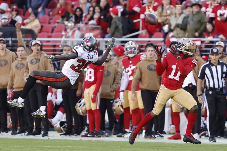 El wide receiver Brandon Aiyuk (11), de los 49ers de San Francisco, atrapa un pase en contra de los Buccaneers de Tampa Bay, ante el intento del cornerback Jamel Dean (35) de impedirlo durante la segunda mitad del juego de la NFL, el domingo 19 de noviembre de 2023, en Santa Clara, California. (AP Foto/Josie Lepe)