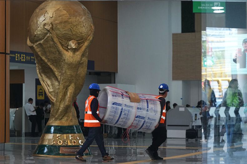 Trabajadores transportan un rollo de espuma junto al trofeo de la Copa Mundial de la FIFA durante una visita guiada para los medios de comunicación al Aeropuerto Internacional Benito Juárez, en preparación para la Copa Mundial de 2026, en la Ciudad de México, el martes 19 de mayo de 2026. (AP Foto/Fernando Llano)