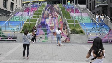 Fans posan junto a un retrato de Taylor Swift pintado en una escalera en el estadio de Wembley en Londres, el miércoles 14 de agosto de 2024, antes de una serie de conciertos de Taylor Swift que comienzan el jueves. (Foto AP/Alastair Grant)