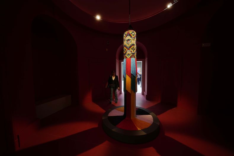 Visitantes miran esculturas del artista Jeffrey Gibson en el pabellón estadounidense en la 60a Bienal de Artes en Venecia, Italia, el martes 16 de abril de 2024. Gibson, un choctaw de Mississippi de ascendencia cherokee, es el primer indígena estadounidense en representar a Estados Unidos en solitario en la Bienal de Venecia, la muestra de arte contemporáneo más antigua del mundo. (Foto AP/Luca Bruno)