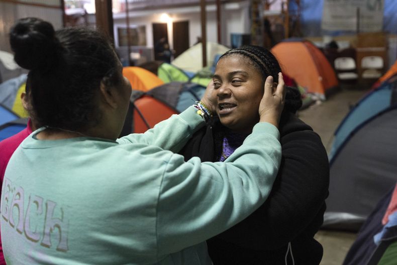 Margelis Rodríguez, a la derecha, de Venezuela, recibe un abrazo de una amiga en un refugio de migrantes donde se aloja con sus dos hijos en Tijuana, México, el miércoles 5 de febrero de 2025. (AP Foto/Gregory Bull)