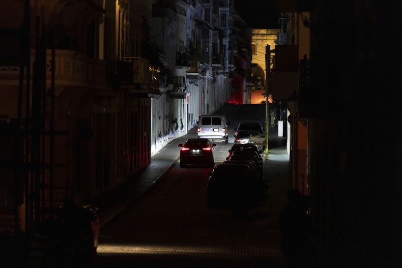 Automóviles transitan por una calle oscura en el Viejo San Juan, Puerto Rico, en medio de un apagón de extensión nacional, el miércoles 16 de abril de 2025. (AP Foto/Alejandro Granadillo)