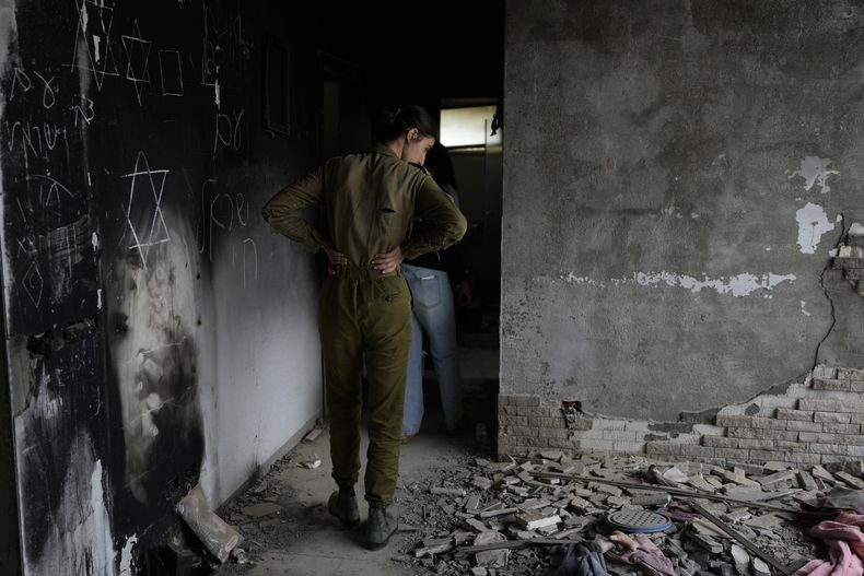 Una soldado israelí observa una casa marcada por la batalla en el kibutz Beeri, una granja comunal israelí en la frontera con Gaza, en el primer aniversario del ataque de Hamás contra Israel el lunes 7 de octubre de 2024. (AP Foto/Ohad Zwigenberg)