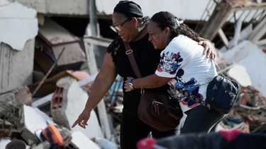 Sobrevivientes señalan un cuerpo atrapado entre los escombros dos días después de que los terremotos azotaran Catia La Mar, Venezuela, el viernes 26 de junio de 2026. (AP foto/Fernando Vergara)