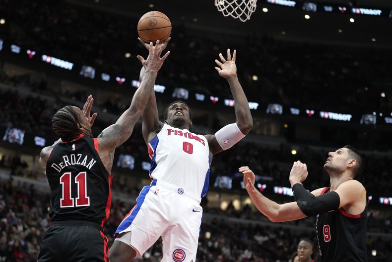 Jalen Duren de los Pistons de Detroit lanza el balón bajo presión de DeMar DeRozan y Nikola Vucevic de los Bulls de Chicago en el encuentro del martes 27 de febrero del 2024. (AP Foto/Charles Rex Arbogast)
