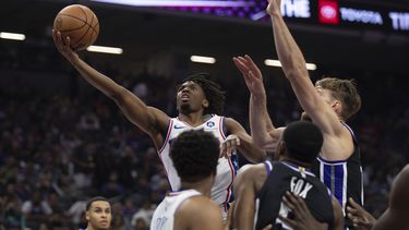 El jugador de los 76ers de Filadelfia, Tyrese Maxey, intenta encestar ante Domantas Sabonis (derecha), de los Kings de Sacramento, en el partido de la NBA que enfrentó a ambos equipos, en Sacramento, California, el 25 de marzo de 2024. (AP Foto/José Luis Villegas)