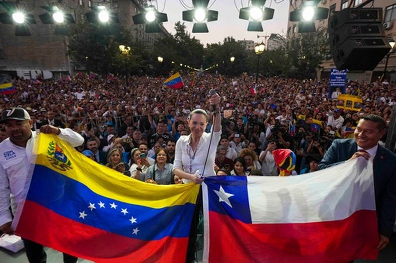 La líder opositora venezolana María Corina Machado junto con las banderas de Venezuela y Chile en una reunión con la comunidad venezolana en Santiago de Chile, el 12 de marzo del 2026. (AP foto/Esteban Felix)