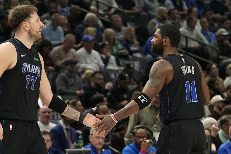 Kyrie Irving (11), de los Mavericks de Dallas, es felicitado por su compañero de equipo Luka Doncic (77) durante la primera mitad del juego de baloncesto de la NBA en contra del Jazz de Utah, en Dallas, el miércoles 6 de diciembre de 2023. (AP Foto/LM Otero)