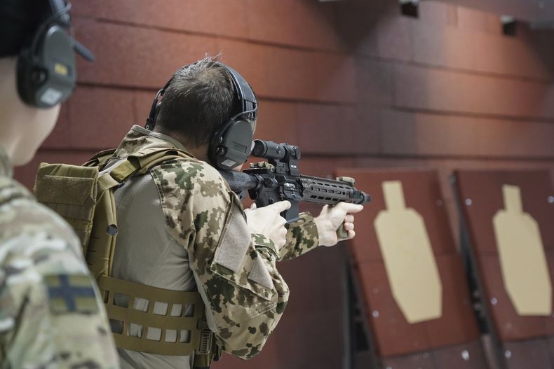 Miembros de la Asociación de Reservistas de Vantaa practican en un campo de tiro en un almacén de Kerava, en las afueras de Helsinki, Finlandia, el lunes 2 de diciembre de 2024. (AP foto/James Brooks)