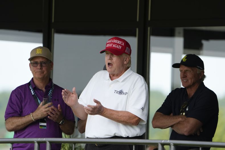 El expresidente Donald Trump, Greg Norman, director general de LIV Golf, a la derecha, y Paul Myler, jefe adjunto de la misión de la embajada australiana en Washington, a la izquierda, presencian la segunda ronda del torneo LIV Golf, en el Club de Golf Trump National, en Sterling, Virginia, el 27 de mayo de 2023. (AP Foto/Alex Brandon)