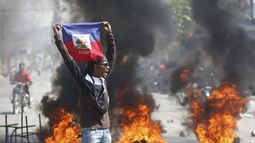 Un manifestante muestra una bandera haitiana durante una protesta para exigir la renuncia del primer ministro del país, Ariel Henry, en Puerto Príncipe, Haití, el 1 de marzo de 2024. (AP Foto/Odelyn Joseph)