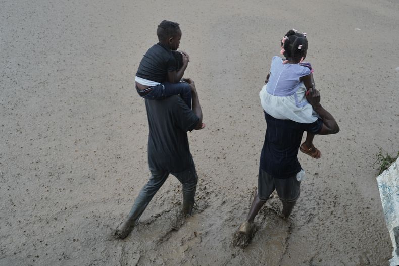ARCHIVO - Dos personas vadean una calle inundada tras el huracán Melissa en Petit-Goave, Haití, el 30 de octubre de 2025. (AP Foto/Odelyn Joseph, Archivo)