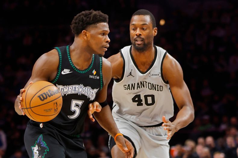 Anthony Edwards (5), escolta de los Timberwolves de Minnesota, se mueve alrededor de Harrison Barnes (40), alero de los Spurs de San Antonio, en el primer cuarto de un juego de baloncesto de la NBA el domingo 30 de noviembre de 2025, en Mineápolis. (AP Photo/Bruce Kluckhohn)