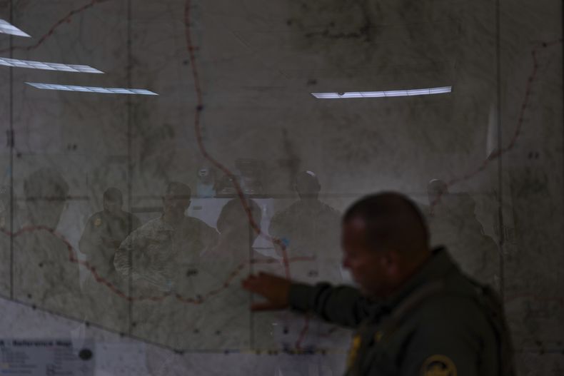 La silueta de varios efectivos del ejército de Estados Unidos se refleja en un mapa mientras escuchan a José Luis Maheda durante una sesión informativa en las instalaciones de la Patrulla Fronteriza, el 22 de julio de 2025, en Nogales, Arizona. (AP Foto/Jae C. Hong)