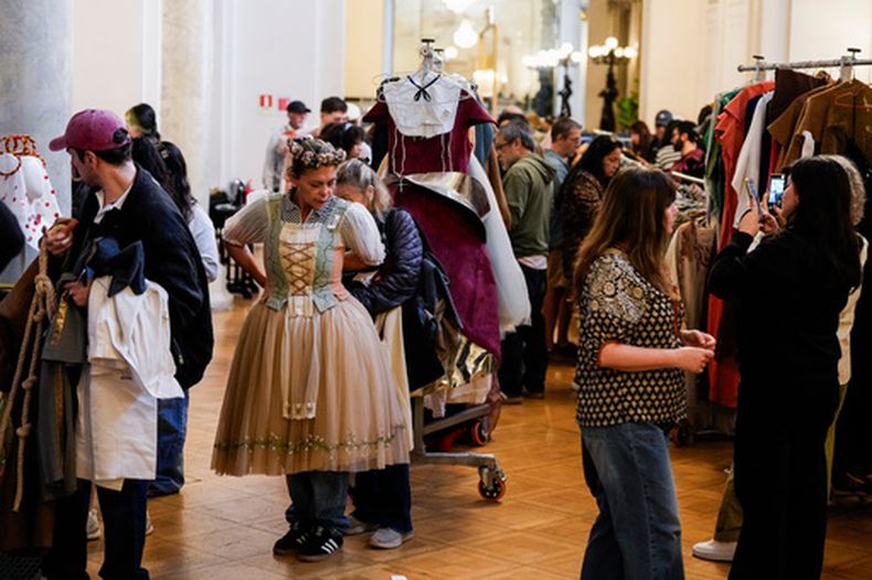 Compradores hojean disfraces y ropa de producciones teatrales, de ballet y de ópera en una venta pública en el Teatro Municipal de Santiago de Chile, el viernes 30 de octubre de 2026, antes de las celebraciones de Halloween. (Foto AP/Esteban Félix)