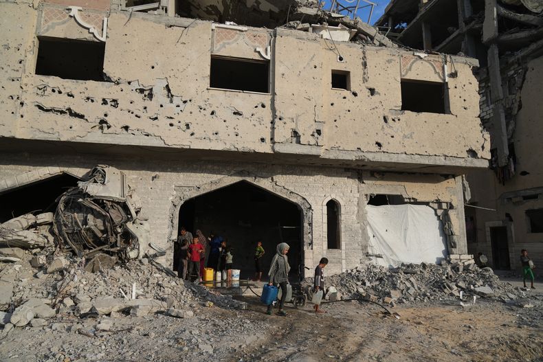 Palestinos desplazados recogen agua en un edificio destruido, en Jan Yunis, en la Franja de Gaza, el 18 de octubre de 2025. (AP Foto/Jehad Alshrafi)
