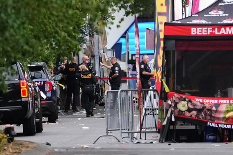 Un fotógrafo de escena de crimen llega mientras las fuerzas de seguridad investigan el lugar de un tiroteo en el Seattle Center durante el festival gastronómico Bite of Seattle el domingo 26 de julio de 2026 en Seattle. (AP Foto/Lindsey Wasson)