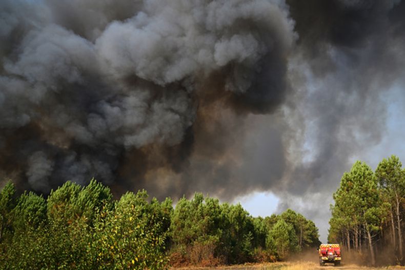 Una nube de humo se eleva hacia el cielo mientras los bomberos tratan de extinguir un incendio en un bosque cerca de Blagon, en el suroeste de Francia, el 29 de julio de 2026. (AP Foto/Emma Da Silva)
