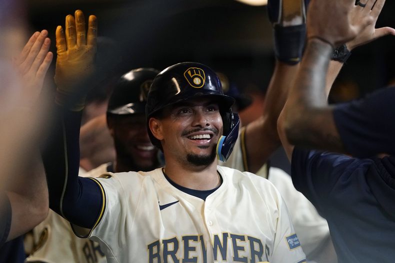 El dominicano Willy Adames, de los Cerveceros de Milwaukee, es felicitado en la cueva luego de batear un jonrón de tres carreras ante los Piratas de Pittsburgh, el miércoles 10 de julio de 2024 (AP Foto/Aaron Gash)