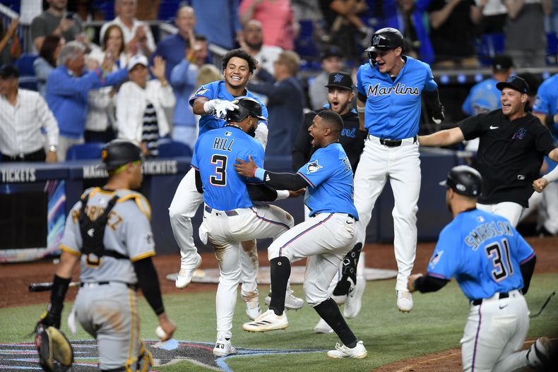 Jugadores de los Marlins de Miami celebran después de que Derek Hill (3) anotara la carrera de la victoria frente a los Piratas de Pittsburgh el domingo 30 de marzo de 2025, en Miami. (AP Foto/Michael Laughlin)