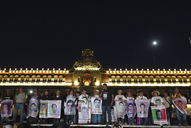 ARCHIVO - Familiares de los 43 estudiantes que desaparecieron en la localidad de Ayotzinapa sostienen carteles con las imágenes y nombres de sus parientes en el noveno aniversario de su desaparición, frente al Palacio Nacional, el 26 de septiembre de 2023, en la Ciudad de México. (AP Foto/Marco Ugarte, Archivo)