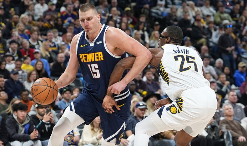 El pívot de los Nuggets de Denver Nikola Jokic, izquierda, ataca la canasta pasando sobre Jalen Smith (25) alero de los Pacers de Indiana, en la segunda mitad del juego de baloncesto de la NBA, el domingo 14 de enero de 2024, en Denver. (AP Foto/David Zalubowski)