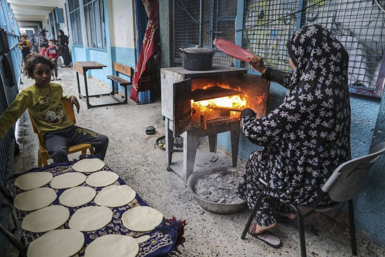 Una mujer palestina que tuvo que dejar su hogar debido a los bombardeos israelíes cocina en una escuela operada por la ONU, el lunes 27 de noviembre de 2023, en la Ciudad de Gaza. (AP Foto/Mohammed Hajjar)