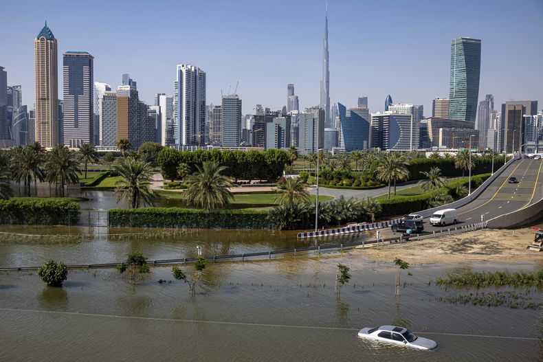 ARCHIVO – Un vehículo abandonado en una inundación que cubre un importante camino en Dubái, Emiratos Árabes Unidos, el jueves 18 de abril de 2024, tras fuertes tormentas eléctricas. (AP Foto/Christopher Pike, Archivo)