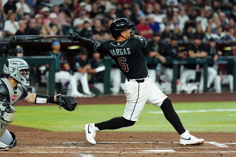 Ildemaro Vargas (6), de los Diamondbacks de Arizona, observa el vuelo de la pelota de su jonrón de tres carreras, mientras el receptor Edgar Quero, izquierda, de los Medias Blancas de Chicago, durante la segunda entrada del juego de béisbol de Grandes Ligas, el miércoles 22 de abril de 2026, en Phoenix. (AP Foto/Ross D. Franklin)