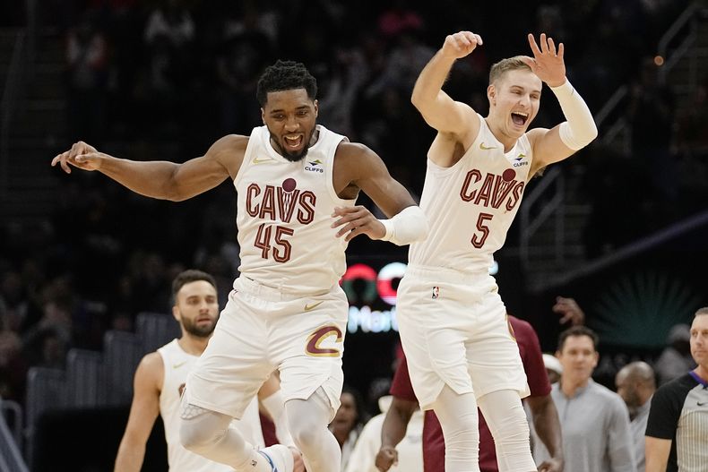 Donovan Mitchell (45) y Sam Merrill, de los Cavaliers de Cleveland, festejan una jugada de tres puntos en la prórroga del duelo ante los Rockets de Houston, el lunes 18 de diciembre de 2023 (AP Foto/Sue Ogrocki)