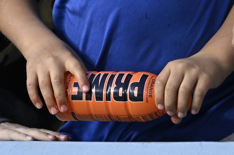 Un niño sostiene una bebida PRIME Hydration, que no contiene cafeína, antes de un partido de béisbol entre los Dodgers de Los Ángeles y los Diamondbacks de Arizona, el 31 de marzo de 2023, en Los Ángeles. PRIME también produce una bebida energética con alto contenido de cafeína que se ha ganado una popularidad viral entre los niños y enfrenta el escrutinio de legisladores federales y expertos en salud. El domingo 9 de julio de 2023, el senador Chuck Schumer pidió a la Administración de Drogas y Alimentos que investigara PRIME. (Foto AP/Mark J. Terrill, Archivo)