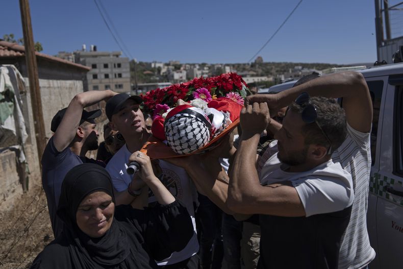 Maisa al-Bayed (izquierda) carga con el cadáver de su hijo, Muhammad al-Bayed, de 17 años, durante su funeral, en la localidad cisjordana de Jifna, al norte de Ramallah, el 22 de julio de 2023. (AP Foto/Nasser Nasser)