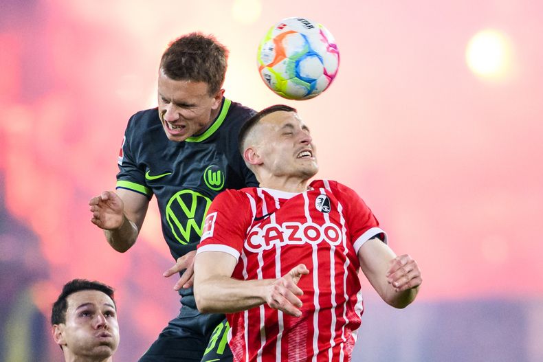 Yannick Gerhardt, del Wolfsburg, a la izquierda, y Roland Sallai, del Freiburg, disputan un balón durante el partido del viernes 19 de mayo de 2023, en Freiburgo, Alemania. (Tom Weller/dpa via AP)