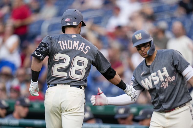 Lane Thomas, de los Nacionales de Washington, festeja con el dominicano Jeimer Candelario, luego de batear un jonrón ante los Gigantes de San Francisco, el viernes 21 de julio de 2023 (AP Foto/Alex Brandon)