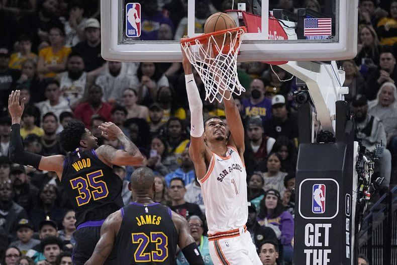 Victor Wembanyama, pívot de los Spurs de San Antonio, encesta frente a Christian Wood (35) y LeBron James, de los Lakers de Los Ángeles, el viernes 15 de diciembre de 2023 (AP Foto/Eric Gay)