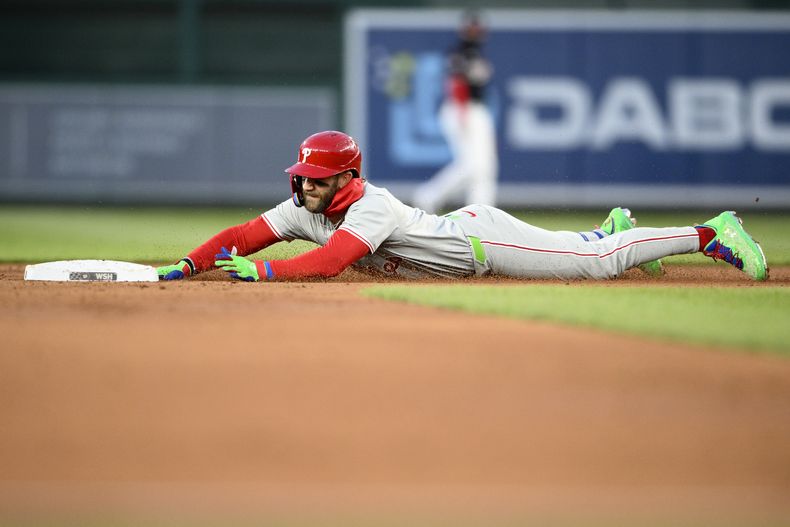 Bryce Harper, de los Filis de Filadelfia, se desliza en la intermedia al conectar un doble en el tercer inning del juego del viernes 5 de abril de 2024, ante los Nacionales de Washington (AP Foto/Nick Wass)