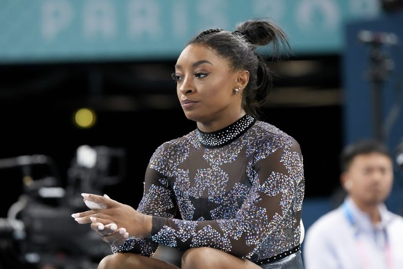 Simone Biles se sienta al costado la viga de equilibrio durante la ronda clasificatoria de la gimnasia de los Juegos Olímpicos de París, el domingo 28 de julio de 2024. (AP Foto/Charlie Riedel)