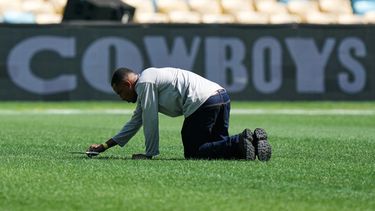 Un trabajador corta el césped con tijeras en el terreno de juego previo a un partido de fútbol americano de la NFL entre los Cowboys de Dallas y los Ravens de Baltimore en Río de Janeiro, el 26 de septiembre de 2026. (Foto AP/Fernando Llano)
