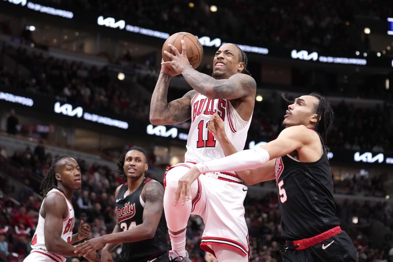 DeMar DeRozan (11), de los Bulls de Chicago, conduce hacia la canasta y recibe una falta de Dalano Banton, de los Trail Blazers de Portland, a la derecha, durante la primera mitad de un partido de baloncesto de la NBA, el lunes 18 de marzo de 2024, en Chicago. (AP Foto/Charles Rex Arbogast)