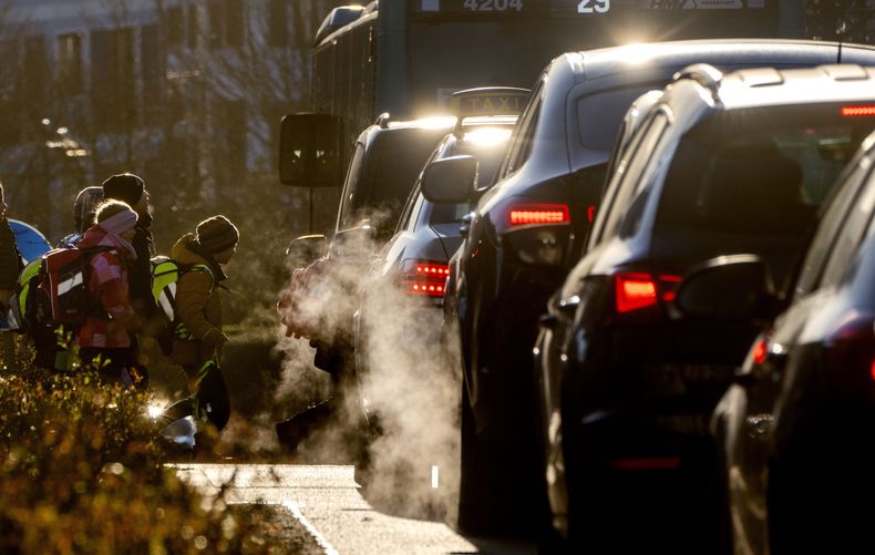 Automóviles liberan emisiones contaminantes mientras los niños van a la escuela en Fráncfort, Alemania, el 27 de febrero de 2023. (Foto AP/Michael Probst, archivo)