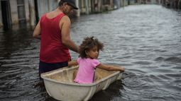 Jesús Hernández con su nieta Angelina en una calle inundada tras el paso del huracán Helene en Batabano, provincia de Mayabeque, Cuba, el 26 de septiembre del 2024. (Foto AP /Ramon Espinosa)