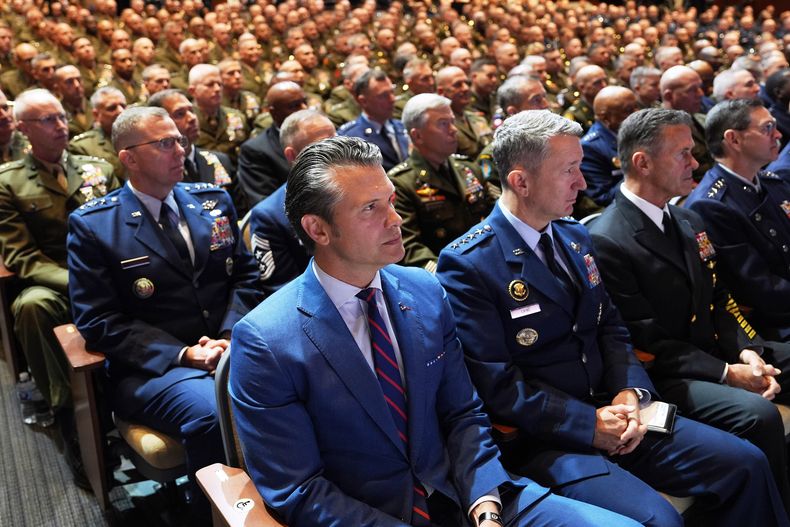 El secretario de Defensa Pete Hegseth (al centro), sentado junto al jefe del Estado Mayor Conjunto, general de la Fuerza Aérea Dan Caine (tercero desde la derecha), y altos mandos militares estadounidenses, escuchan el discurso del presidente Donald Trump en la Base del Cuerpo de Infantería de Marina de Quantico, el martes 30 de septiembre de 2025, en Quantico, Virginia. (AP Foto/Evan Vucci)