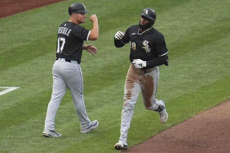 Luis Robert Jr., derecha, de Medias Blancas de Chicago, es felicitado por el coach de tercera Justin Jirschele (17) mientras pasa por tercera base después de batear un cuadrangular solitario frente al lanzador Bailey Falter, de los Piratas de Pittsburgh, durante la cuarta entrada del juego de béisbol de Grandes Ligas el viernes 18 de julio de 2025. (AP Foto/Gene J. Puskar)