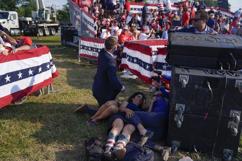 Personas se cubren durante un mitin de campaña del expresidente de EEUU y virtual candidato presidencial republicano Donald Trump el sábado 13 de julio de 2024 en Butler, Pensilvania. (AP Foto/Evan Vucci)