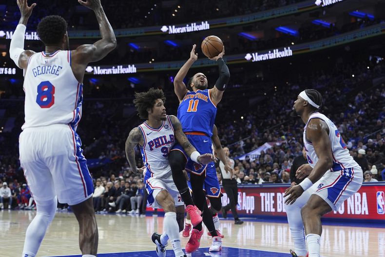 Jalen Brunson (11), de los Knicks de Nueva York, se alza para intentar un tiro al aro ante Kelly Oubre Jr. (9), de los 76ers de Filadelfia, durante la primera mitad del juego de baloncesto de la NBA, el miércoles 15 de enero de 2025, en Filadelfia. (AP Foto/Matt Slocum)