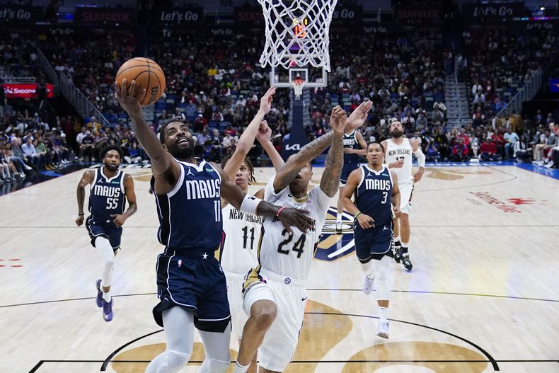 Kyrie Irving (11), de los Mavericks de Dallas, ataca la canasta ante la presión defensiva de Jordan Hawkins (24) y guard Dyson Daniels (11), de los Pelicans de Nueva Orleans, en la primera mitad del juego de baloncesto de la NBA, el domingo 12 de noviembre de 2023. (AP Foto/Gerald Herbert)