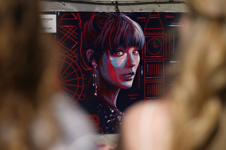 La gente mira un nuevo retrato mural de Taylor Swift diseñado por Kate Clayton que se presentó en Shoreditch, en el este de Londres, el martes 13 de agosto de 2024. (AP Photo/Alastair Grant)