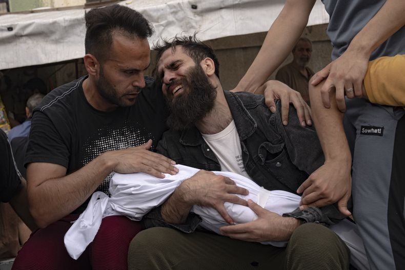 Palestinos lloran a sus familiares muertos en un bombardeo israelí sobre la Franja de Gaza, en una morgue en Jan Yunis, el 29 de octubre de 2023. (AP Foto/Fatima Shbair)